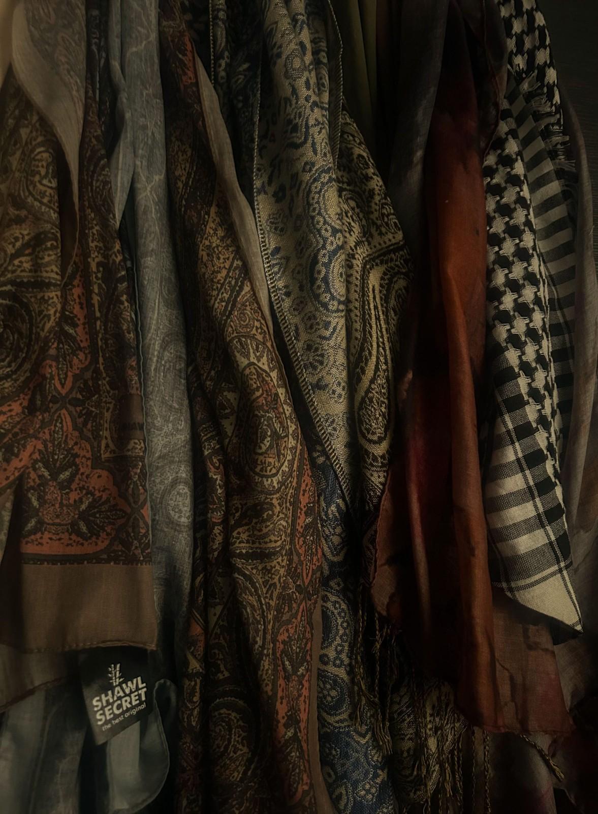 Intricately patterned scarves hanging in a dim light, showcasing cultural textile design.